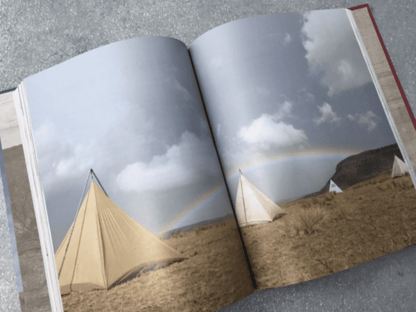 Open book with tents and a rainbow.